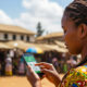 African woman using mobile money on a smartphone, depicting the continent’s rapid digital disruption and mobile payment adoption.