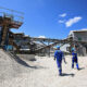 Zimbabwe lithium mine with heavy machinery, highlighting the country's plan to ban raw lithium concentrate exports by 2027 for local processing and EV battery production.