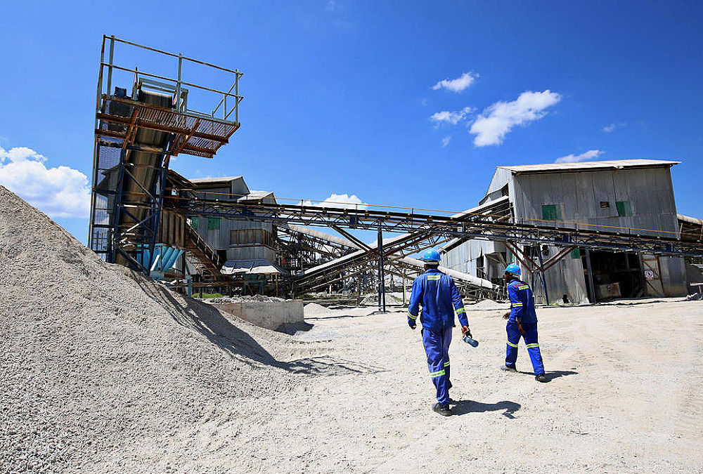 Zimbabwe lithium mine with heavy machinery, highlighting the country's plan to ban raw lithium concentrate exports by 2027 for local processing and EV battery production.