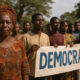 African citizens in traditional attire marching peacefully for democracy, symbolizing cultural diversity and the call for accountable, rights-based governance across the continent.