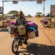 African trader transporting goods across a rural border crossing, symbolizing the rise of informal trade amid regional barriers in East Africa.