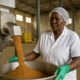 African woman working in an agro-processing plant, turning raw agricultural products into finished goods to promote local industrialization and economic transformation.