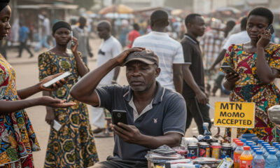 A frustrated street vendor in Ghana waiting for a mobile money payment during a nationwide mobile money outage, highlighting the vulnerability of the country’s cashless economy.