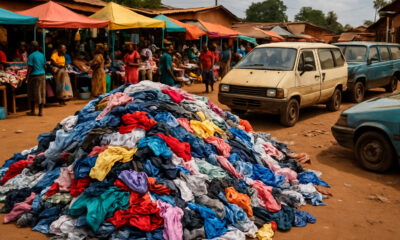 Pile of used clothing and old vehicles at a market in Africa, symbolizing the continent’s role as the world’s unpaid sustainability buffer — representing over $150 billion in unclaimed environmental credits from decades of absorbing Global North waste.