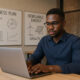 A young African entrepreneur working on a laptop in a co-working space in Kimberley, Northern Cape. Background includes whiteboards with business plans and renewable energy diagrams, symbolizing local innovation potential hindered by lack of venture capital access.