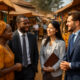 A diverse group of business professionals in an African market setting, engaged in conversation - highlighting the importance of listening, cultural understanding, and collaboration in international business. The image symbolizes cross-cultural communication, local partnership, and market entry success through active listening.