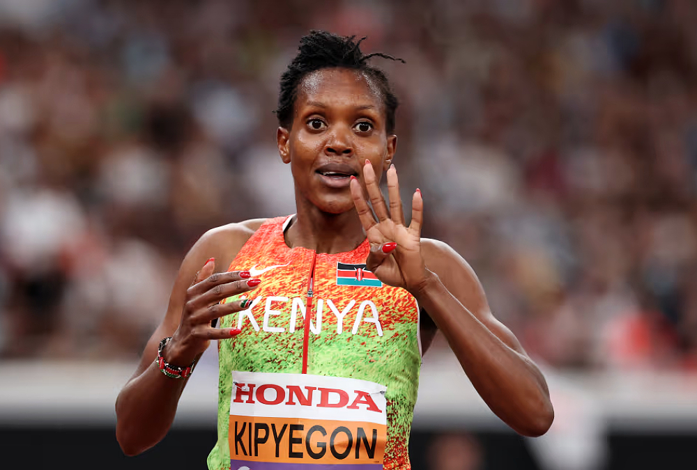 Faith Kipyegon crosses finish line to win 4th 1500m world title at Tokyo World Athletics Championships, wearing Kenyan kit and raising arms in victory.