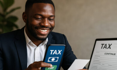 African business owner using mobile phone to pay taxes digitally, representing Africa’s digital tax revolution with mobile money, e-filing, and blockchain compliance tools.