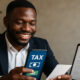 African business owner using mobile phone to pay taxes digitally, representing Africa’s digital tax revolution with mobile money, e-filing, and blockchain compliance tools.
