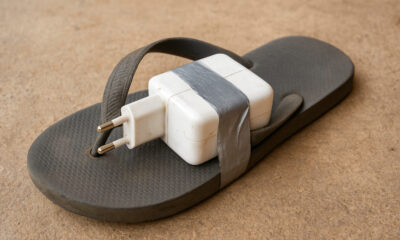 A portable power adapter duct-taped to a flip-flop sandal - symbolizing African innovation under constraints, where resourcefulness solves real problems with limited resources.
