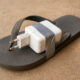 A portable power adapter duct-taped to a flip-flop sandal - symbolizing African innovation under constraints, where resourcefulness solves real problems with limited resources.