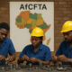 African factory workers assembling goods beside a map of the AfCFTA trade bloc, symbolizing regional industrialization and value addition.