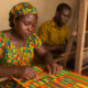 Ghanaian artisans weaving Kente cloth, symbolizing the country’s first Geographical Indication and the protection of African cultural heritage.