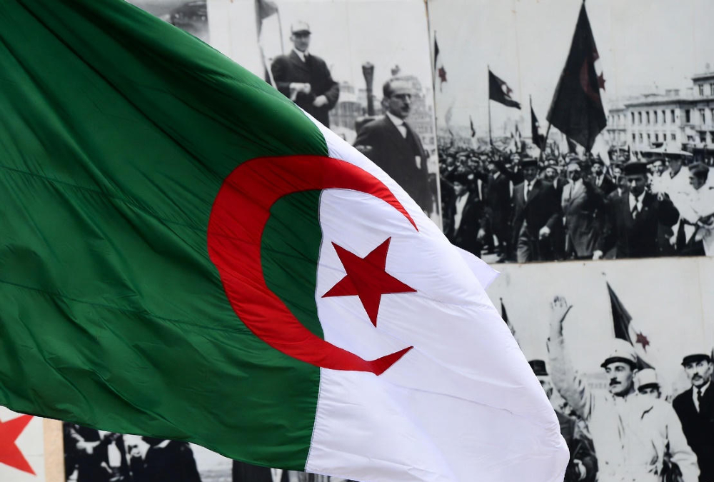 Algerian flag alongside historical imagery symbolizing resistance to French colonial rule, representing Algeria's new law declaring colonialism a crime against humanity.