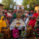 African families and neighbors of different faiths celebrating Christmas together in unity, sharing meals and joy - embodying Ubuntu, interfaith harmony, and communal spirit across diverse cultures.