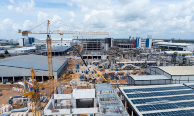 African industrial transformation driven by catalytic capital - cranes at a construction site in an industrial park, solar panels, agro-processing facilities, and local entrepreneurs collaborating, symbolizing real investment beyond reports and feasibility studies.