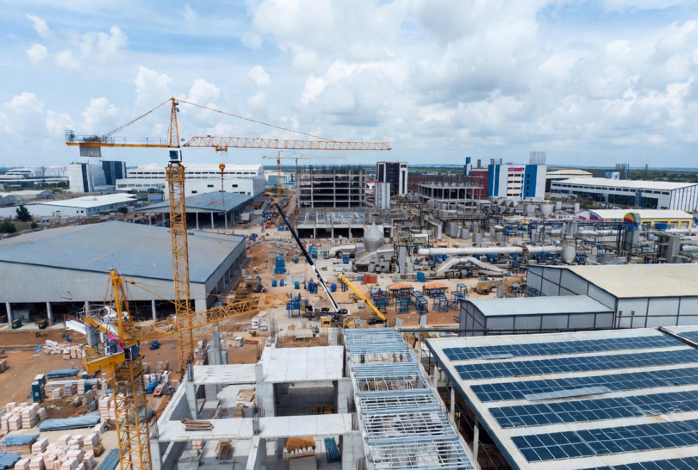 African industrial transformation driven by catalytic capital - cranes at a construction site in an industrial park, solar panels, agro-processing facilities, and local entrepreneurs collaborating, symbolizing real investment beyond reports and feasibility studies.