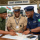 African border officials from neighboring countries collaborating at a joint border post, symbolizing the needed harmonization and trust-building.