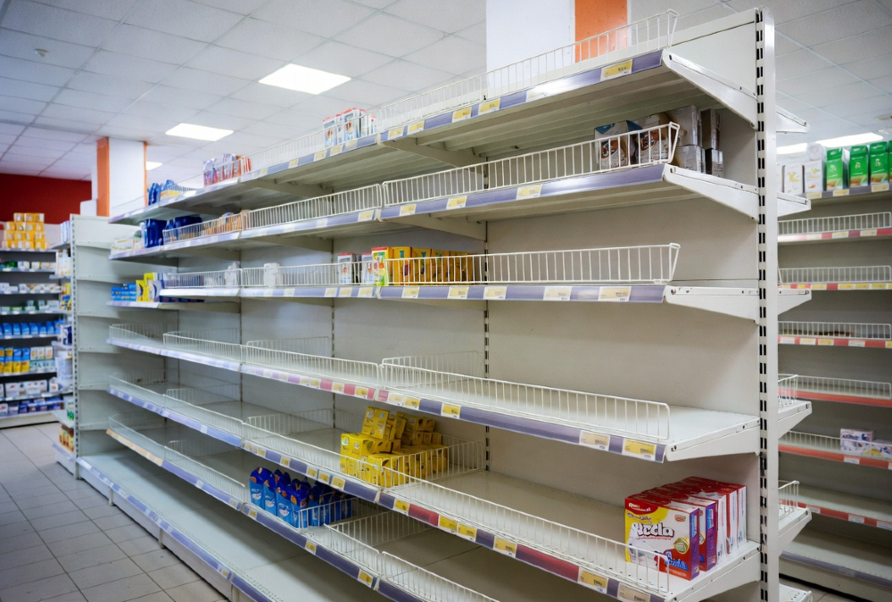 Empty retail shelves in an African store, symbolizing the gap between consumer demand and local manufacturing capacity.