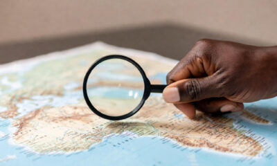 A magnifying glass held over a map of Africa by an African hand, shifting the focus from external to internal analysis.