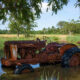 Rusted tractor submerged in a river in rural Kenya, symbolizing failed Western agricultural technology transfer in the developing world.
