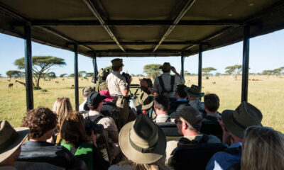 Group of diverse tourists on a safari vehicle viewing wildlife in the Maasai Mara, Kenya.