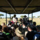 Group of diverse tourists on a safari vehicle viewing wildlife in the Maasai Mara, Kenya.
