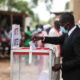 A voter casting a ballot in Africa, representing the 2026 elections that will filter disciplined multinational capital from undisciplined investment.