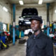 African entrepreneur at automotive service center, illustrating lowered entry barriers under the agency retail model
