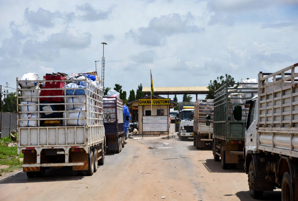 Ghana-Togo border post with Trucks with goods in transit, representing the tension between formal trade frameworks and informal reality in West Africa