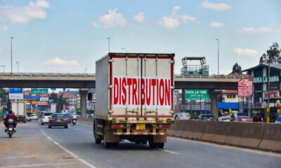 A logistics truck navigating a busy Kenyan market street, representing the challenges and opportunities of distribution strategy for international manufacturers entering the East Africa consumer market.