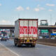 A logistics truck navigating a busy Kenyan market street, representing the challenges and opportunities of distribution strategy for international manufacturers entering the East Africa consumer market.