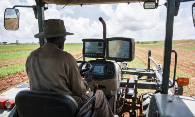 African farmer operating precision agriculture tractor with GPS dashboard and real-time soil data display in Zambia