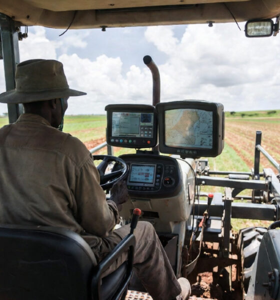 African farmer operating precision agriculture tractor with GPS dashboard and real-time soil data display in Zambia