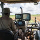 African farmer operating precision agriculture tractor with GPS dashboard and real-time soil data display in Zambia