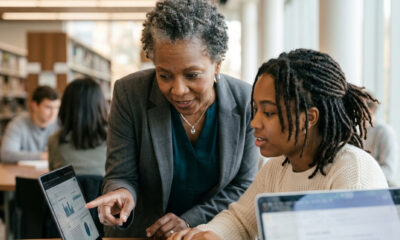 Older Black mentor guiding young Black student with laptop, reflecting importance of visible pathways and support.