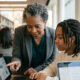 Older Black mentor guiding young Black student with laptop, reflecting importance of visible pathways and support.