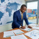 African business owner reviewing export readiness checklist with global trade maps, shipping containers, compliance documents, and supply chain planning for international markets