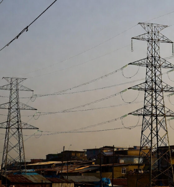 High-voltage power lines stretching over informal settlements in Africa and the Caribbean, where homes below remain without electricity, illustrating energy inequality and lack of grid access despite nearby infrastructure