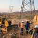 Construction workers building power lines in rural Africa, representing the need for bulldozers over frequent elections.