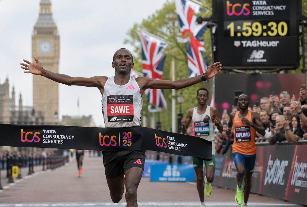 Sebastian Sawe crossing the finish line at the London Marathon, breaking the sub-two-hour marathon record with a historic 1:59:30 performance amid cheering crowds.