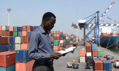 An African export trader reviewing shipment documents at a busy port, with cargo containers and freight vessels in the background, representing China Africa zero-tariff trade opportunities for African nations.