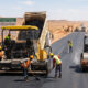 Construction workers paving the Trans-Saharan Highway (TAH 2) linking Algiers to Lagos, part of Africa's infrastructure development initiative