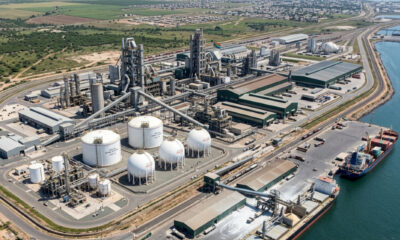 Aerial view of a large modern fertilizer plant complex in Africa with natural gas storage tanks and shipping port, symbolizing the continent's shift from fertilizer import dependency to domestic manufacturing for food security and industrial growth.