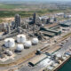 Aerial view of a large modern fertilizer plant complex in Africa with natural gas storage tanks and shipping port, symbolizing the continent's shift from fertilizer import dependency to domestic manufacturing for food security and industrial growth.