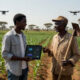 Researcher-farmer bridging academic AI models and real African smallholder farming practices in a field setting, highlighting farmer trust, technology adoption, and context-driven agricultural innovation.