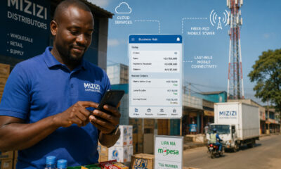 African distributor running a business from a smartphone as a cell tower delivers fiber-fed mobile broadband