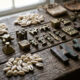 A collection of pre-colonial African currency, including cowrie shells, brass gold weights, and copper crosses, displayed on a rustic wooden surface.